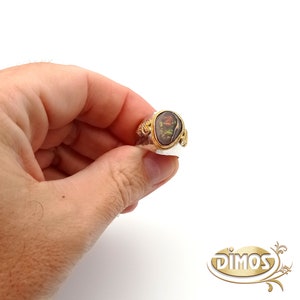 May include: A gold ring with a brown and green gemstone set in a decorative gold setting.