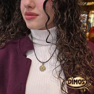 Octagonal silver and gold pendant featuring a central blue cubic zirconia surrounded by four rows of clear cubic zirconia and gold floral motifs