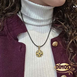Octagonal silver and gold pendant featuring a central blue cubic zirconia surrounded by four rows of clear cubic zirconia and gold floral motifs