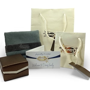 May include: An assortment of jewelry packaging and accessories. Includes two cream-colored shopping bags with white rope handles, a gray polishing cloth with a dark brown band, a brown jewelry box, and a business card with the text "Welcome to Dimos family."