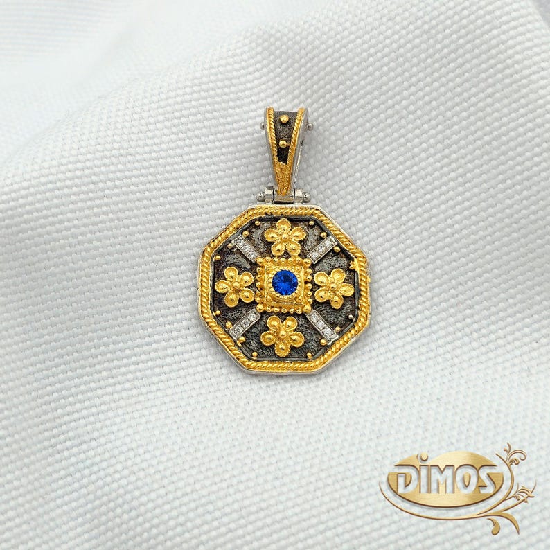 Octagonal silver and gold pendant featuring a central blue cubic zirconia surrounded by four rows of clear cubic zirconia and gold floral motifs