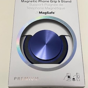 May include: A white box with a blue and silver Popsocket magnetic phone grip and stand. The product is designed for MagSafe devices. The box has the words "Magnetic Phone Grip & Stand" and "PREMIUM" printed on it.