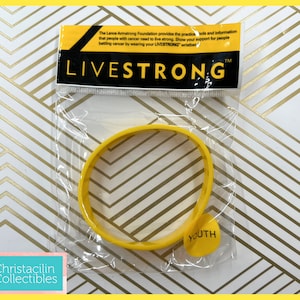 May include: A yellow LIVESTRONG wristband in a clear plastic package. The wristband is made of rubber and has the word "YOUTH" on a small yellow tag. The packaging includes text about the Lance Armstrong Foundation.