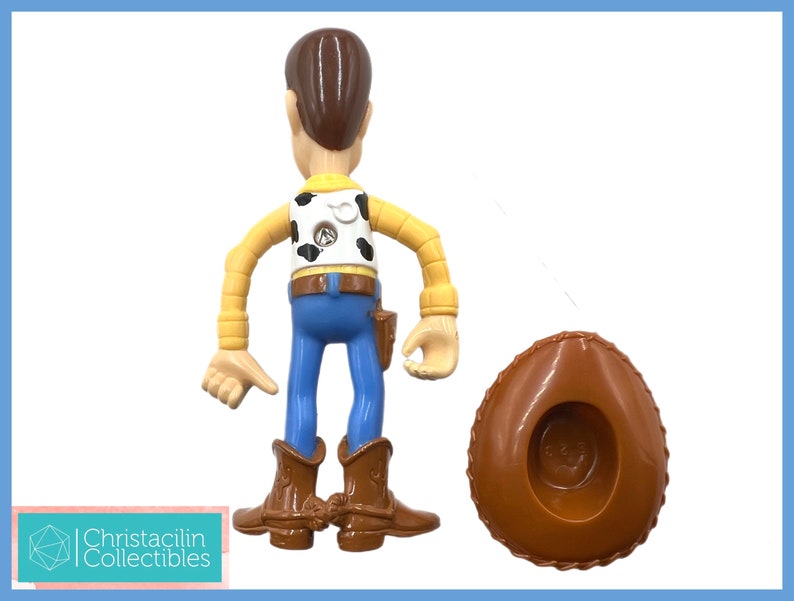 May include: A Woody action figure from the Toy Story franchise. The figure is wearing a cowboy hat, blue jeans, a yellow shirt, and brown boots. The figure is approximately 6 inches tall.