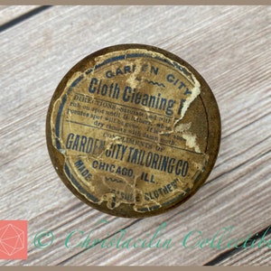 May include: An antique, round metal tin of "Cloth Cleaning Fluid" from Garden City Tailoring Co., Chicago, with a distressed label. The label includes instructions and the text "ISSUE CLOTHES".