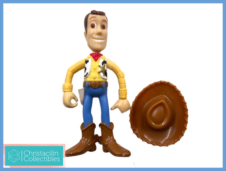 May include: A Woody action figure from the Toy Story franchise, with a brown cowboy hat. The figure is wearing a yellow shirt, blue pants, and brown boots. The figure has a sheriff's badge and a red bandana.