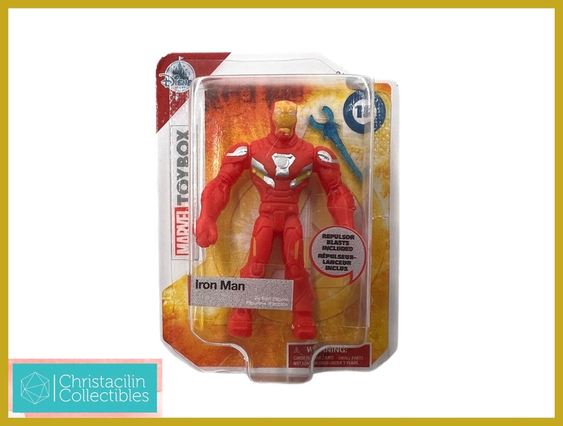 May include: A red Iron Man action figure from the Marvel Toybox series, packaged in a clear plastic blister pack. The figure has a gold helmet and silver accents. The packaging includes the Disney logo and the text "Iron Man".