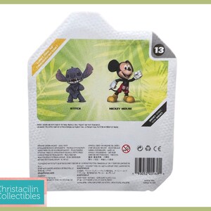 May include: A package featuring two Disney figurines: Stitch and Mickey Mouse. Stitch is a dark blue alien with large ears, and Mickey Mouse is in his classic outfit. The package has a green and white background with the number 13.