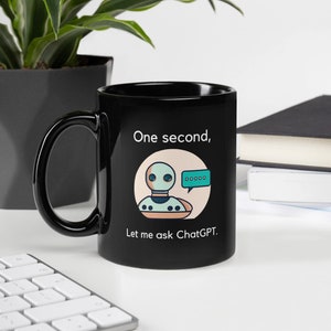 May include: Black coffee mug with a white design featuring a cartoon robot with a speech bubble that says "One second, let me ask ChatGPT."