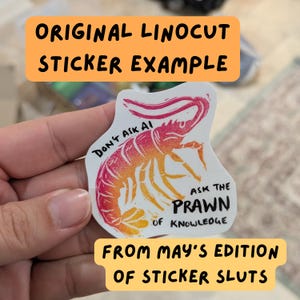 K&ouml;nnte beinhalten: Ein gestanzter Aufkleber mit einer Illustration im Linolschnitt-Stil einer Garnele mit einem rosa-orangen Farbverlauf. Der Text lautet: DON'T ASK AI ASK THE PRAWN OF KNOWLEDGE. Der Aufkleber hat einen wei&szlig;en Hintergrund und eine individuelle Form.