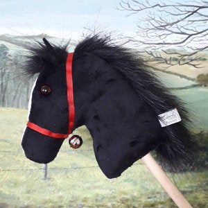 May include: Black plush rocking horse with a red bridle and a bell. The horse has a long black mane and tail. The horse is on a wooden stick. The horse has a label that says "Laurels of the Ponies".