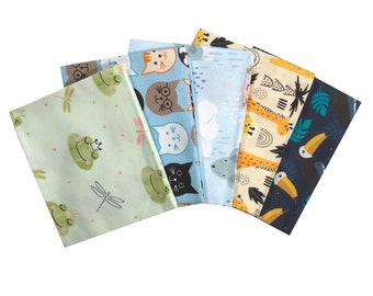May include: Five fabric squares with different animal and nature designs. The squares are in a fan shape with the green square with frogs and dragonflies at the bottom. The other squares feature a cat, a giraffe, a toucan, and a koala.