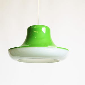 May include: A modern, two-tone pendant light fixture. The top is a vibrant green, transitioning to a white, saucer-shaped bottom. The light hangs from a thin, white cord against a plain white background.