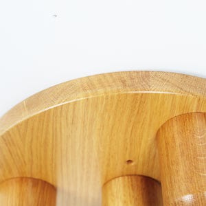 K&ouml;nnte beinhalten: Ein Hocker aus Holz mit einer runden Oberseite und drei Beinen. Der Hocker ist aus hellbraunem Holz gefertigt und hat eine glatte Oberfl&auml;che.