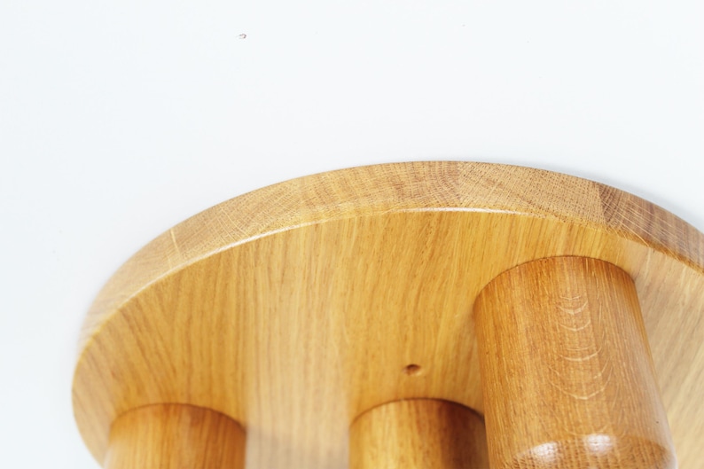K&ouml;nnte beinhalten: Ein Hocker aus Holz mit einer runden Oberseite und drei Beinen. Der Hocker ist aus hellbraunem Holz gefertigt und hat eine glatte Oberfl&auml;che.