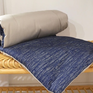 Peut inclure: Un coussin bleu et blanc à motifs avec une housse beige. Le coussin est posé sur un banc en osier.