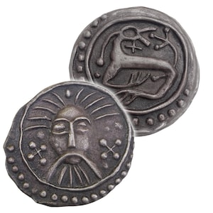May include: Two antique silver-coloured coins. One coin features a detailed face with a beard and radiating lines. The other coin shows a deer-like animal with a cross and other symbols. Both coins have a dotted border.