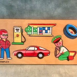 Puede incluir: Un rompecabezas de madera con cinco piezas: un coche rojo, una gasolinera, una llanta, un hombre con una camisa a cuadros rojos y blancos y un hombre con un uniforme verde. El rompecabezas está etiquetado como "SIMPLEX".