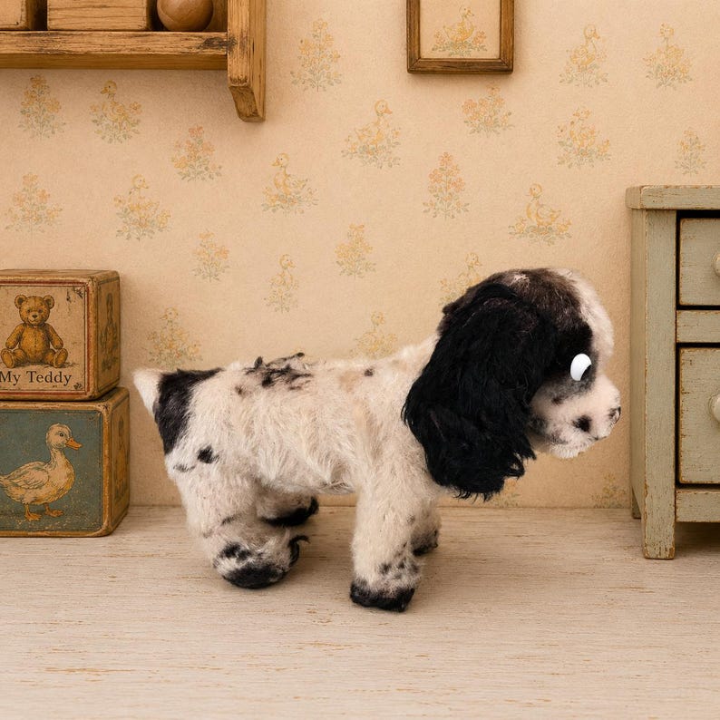 K&ouml;nnte beinhalten: Ein Pl&uuml;schhund mit wei&szlig;em und schwarzem Fell, langen schwarzen Ohren und einem gefleckten Muster auf dem K&ouml;rper. Das Spielzeug steht in einer Profilansicht und zeigt seine weiche Textur sowie detaillierte Gesichtsz&uuml;ge, einschlie&szlig;lich einer dunklen Nase.