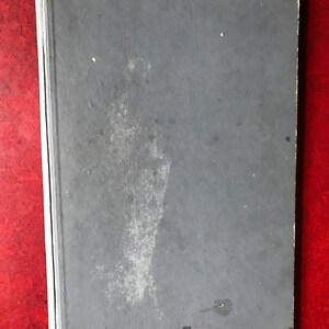 May include: A gray hardcover book with a worn, textured cover. The book has a slight discoloration on the front cover.