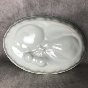 Op de afbeelding: Witte keramische vorm voor het maken van een peer-vormig dessert met een kersenontwerp.