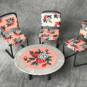 Peut inclure: Un ensemble de table miniature en métal avec trois chaises et une table ronde, à motifs floraux roses et blancs.