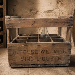 May include: A weathered wooden crate with twelve compartments and a top handle. The front panel features the stamped text D. TESSE WE. VICO VINS LIQUEUR. The crate has a rustic brown finish with visible wood grain and metal nail accents throughout.