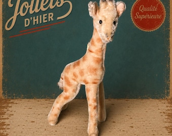 Puede incluir: Un peluche de jirafa con pelaje beige y manchas marrones, de pie. El fondo presenta el texto Jouets D'HIER y un sello circular rojo con el texto Qualité Supérieure, sobre una superficie de color verde oscuro y beige texturizado.