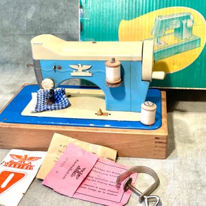 Vintage Casige Spielzeug-Nähmaschine - blaues und beiges Metall - batteriebetriebener und handbetriebener - mit Koffer und Bedienungsanleitung - Deutschland ca. 1950er Jahre