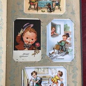 May include: A vintage scrapbook with illustrations of children in various scenes. The scrapbook has a brown cover with a decorative border and the text "Hartelijk Gefeliciteerd" on the front.