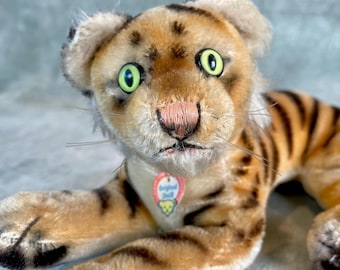 Wunderschöner liegender Steiff Tiger mit Namensschild und fluoreszierenden Augen.