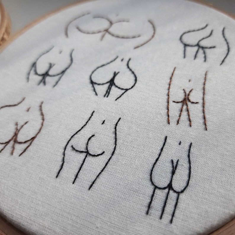 May include: Embroidered hoop art with multiple stylized figures in black and brown thread on a white fabric background.