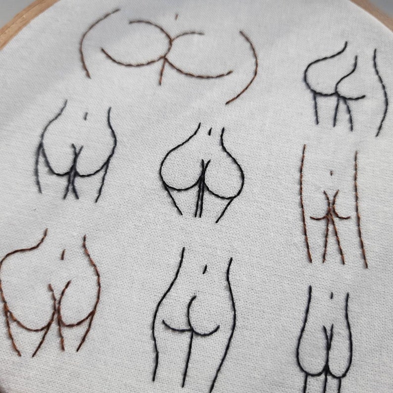 May include: Embroidered hoop art featuring various body shapes in black and brown thread on a white fabric background.