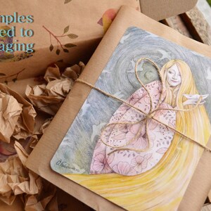 K&ouml;nnte beinhalten: Ein braunes Papierpaket, das mit Schnur gebunden und mit einer Aquarellillustration einer Frau mit langen, flie&szlig;enden Haaren und einem rosafarbenen Blumenmuster verziert ist. Die Illustration ist vor einem dunkelblauen Hintergrund mit wei&szlig;en V&ouml;geln platziert, die um sie herum fliegen.