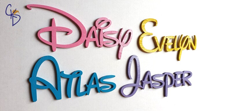 May include: Four wooden names in a Disney font style. The names are Daisy in pink, Evelyn in gold, Atlas in blue, and Jasper in purple.