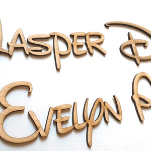 May include: Four wooden names in a cursive font. The names are "Jasper & Daisy" and "Evelyn Atlas".