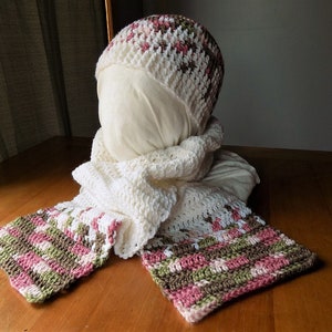 May include: A white crocheted hat with pink and brown stripes, and a matching scarf with pink, brown, and white stripes.
