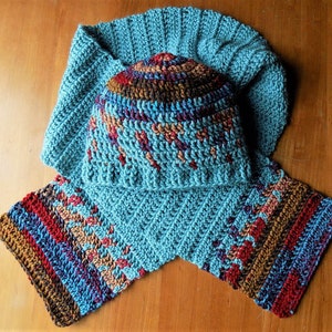 May include: A teal blue crocheted hat and matching scarf with a multi-colored striped pattern in shades of brown, red, and purple.