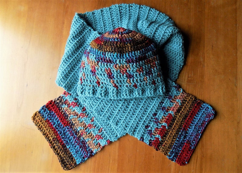 May include: A teal blue crocheted hat and matching scarf with a multi-colored striped pattern in shades of brown, red, and purple.