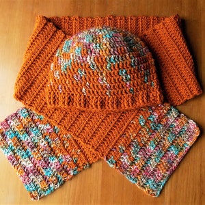 May include: A crocheted hat and scarf set in a rust orange color with a multi-colored yarn pattern. The hat is a slouchy beanie style and the scarf is a long, rectangular shape.