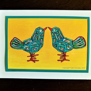 May include: A greeting card with a yellow background featuring two stylized turquoise birds with red legs and beaks facing each other. The card has a teal border and the text "Copyright Violet Trombley 2023" at the bottom.