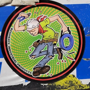 May include: A cartoon illustration of a person wearing a hard hat, blue jeans, and a green shirt holding a spool of blue wire. The background is a green and yellow checkered pattern with the text "RESONATE INDUSTRIAL PRODUCTS" in a black circle.