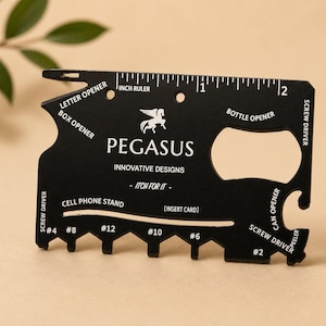 Può includere: Strumento multiuso nero con aprilettere, righello in pollici, apribottiglie e cacciaviti. Lo strumento presenta la scritta "PEGASUS INNOVATIVE DESIGNS" e un logo Pegasus. Funziona anche come supporto per cellulare.