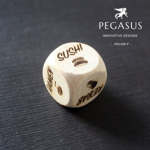 May include: A wooden dice with six sides, each side featuring a different food item: sushi, ramen, kebab, pizza, burger, and tacos. The dice is resting on a black surface.