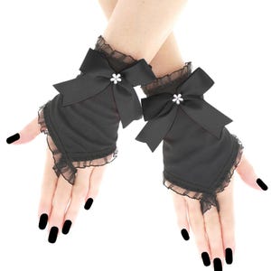 May include: A pair of black fingerless gloves with satin fabric, featuring large bows and lace edging. Each bow is decorated with a small, sparkling detail. The gloves cover the hand up to the knuckles.