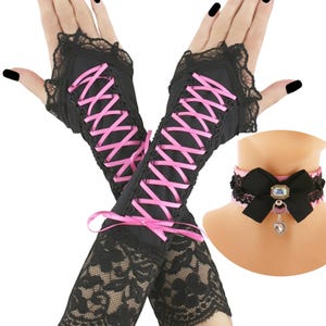May include: A 2PC SET of black lace fingerless gloves with pink ribbon lacing and a matching choker. The choker features a black bow, pink trim, and a decorative pendant. The gloves and choker are designed with a gothic aesthetic.