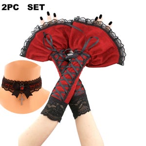 May include: A 2-piece set featuring a red and black choker with a cross pendant and a pair of red and black lace-up arm warmers. The choker has a black bow and a red jewel. The arm warmers have black lace trim.