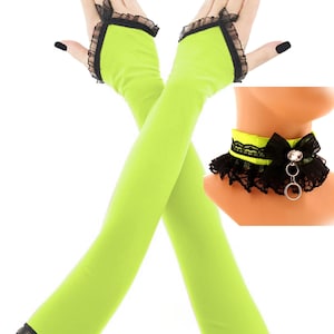 May include: A two-piece set featuring neon green arm warmers with black lace trim and a matching choker. The choker has a black bow and a silver ring detail. The text "2 PC SET" is at the top.