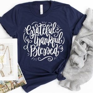 May include: A navy blue t-shirt with white lettering that reads "Grateful Thankful Blessed".