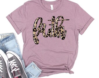 May include: A mauve t-shirt with a leopard print design that says "faith" in a cursive font.